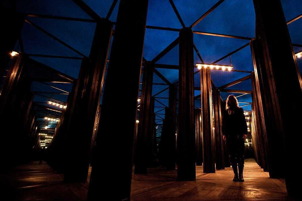 Person standing in a house of mirrors at night. Art installation engineered by Vistek Structural Engineers.